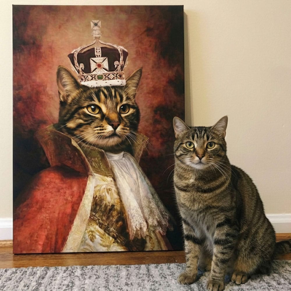 Real cat sitting next to a painting of a cat in regal attire with a crown.