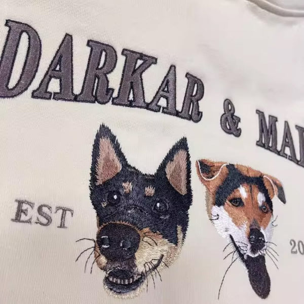 A custom sweatshirt featuring an embroidered pet portrait and personalized text in a varsity style font.