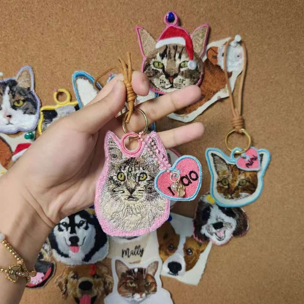A custom pet embroidery keychain featuring the face of a tabby cat.