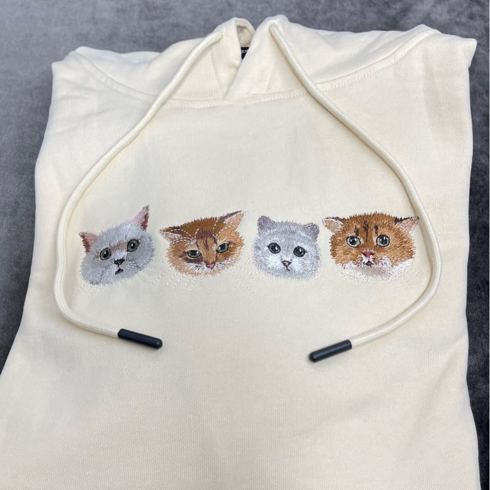 A custom embroidered hoodie featuring portraits of four different pets.