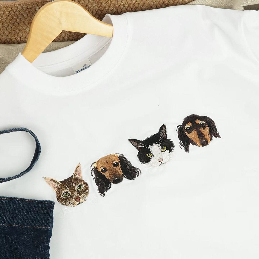 White sweatshirt with embroidered cat and dog faces on a hanger.