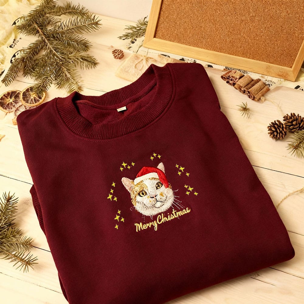 Red custom embroidered pet portrait Christmas sweatshirt featuring a cat wearing a Santa hat.