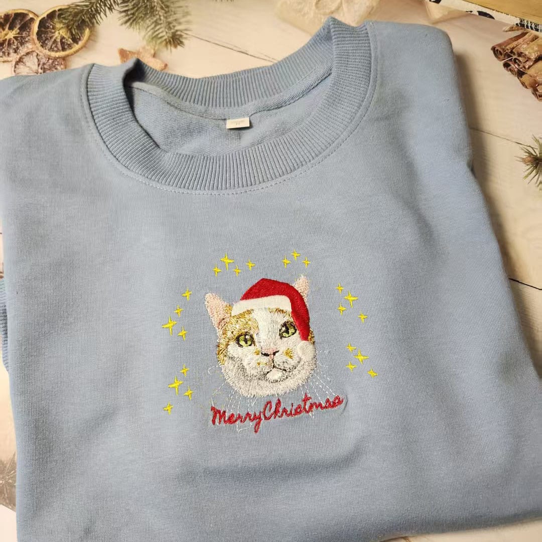 Lightblue custom embroidered pet portrait Christmas sweatshirt featuring a cat wearing a Santa hat.