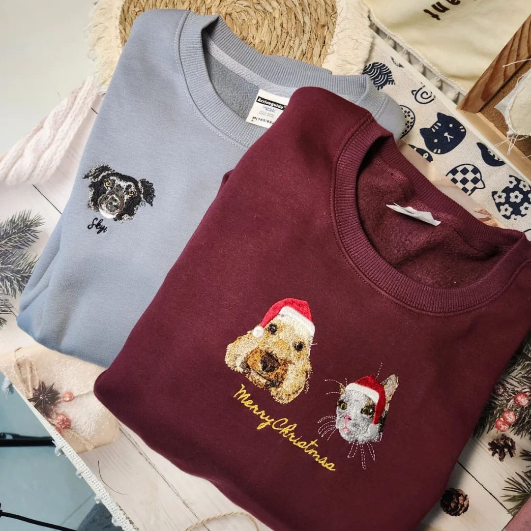 Lightblue and red custom embroidered pet portrait Christmas sweatshirt featuring a cat and dog wearing a Santa hat.