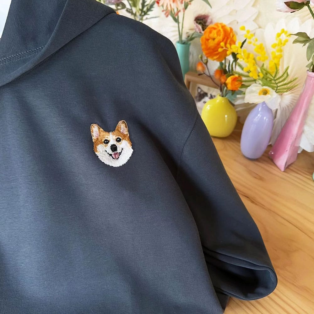 A navy hoodie featuring a custom embroidered pet portrait.