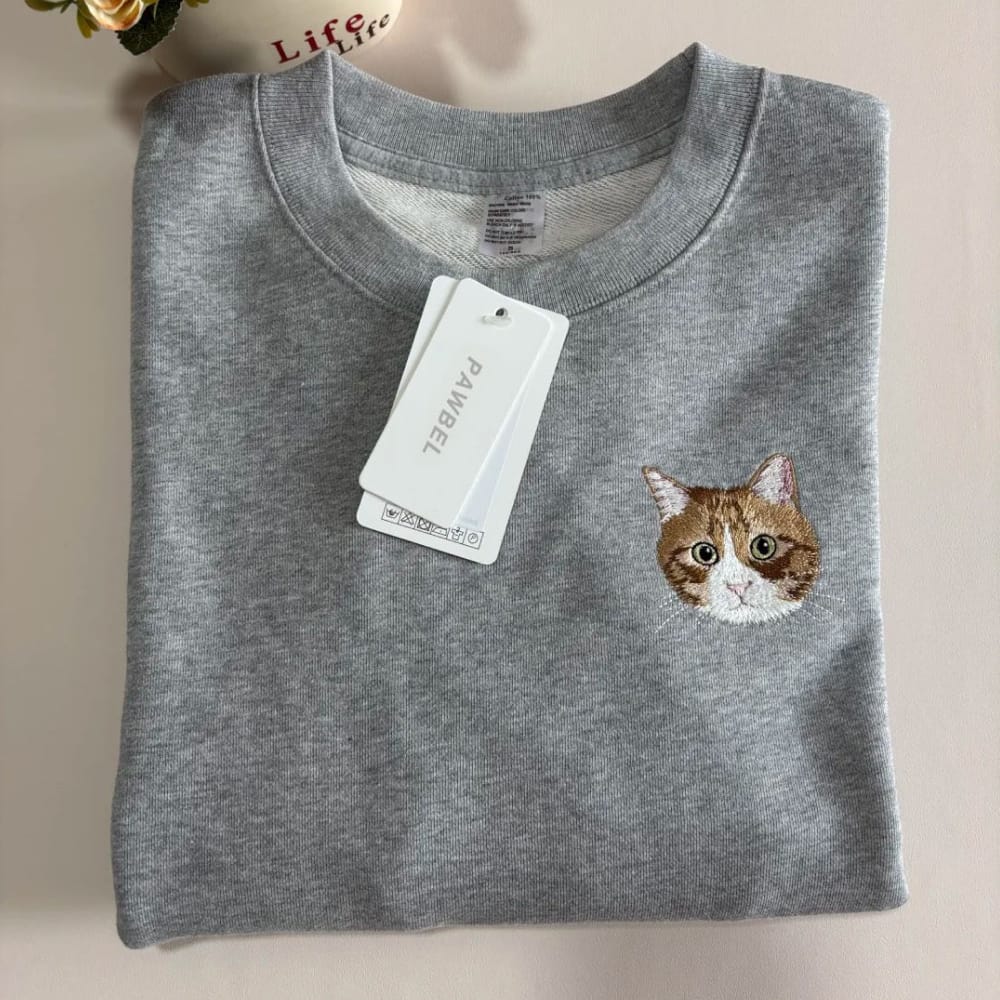 A grey sweatshirt featuring a custom embroidered pet portrait.