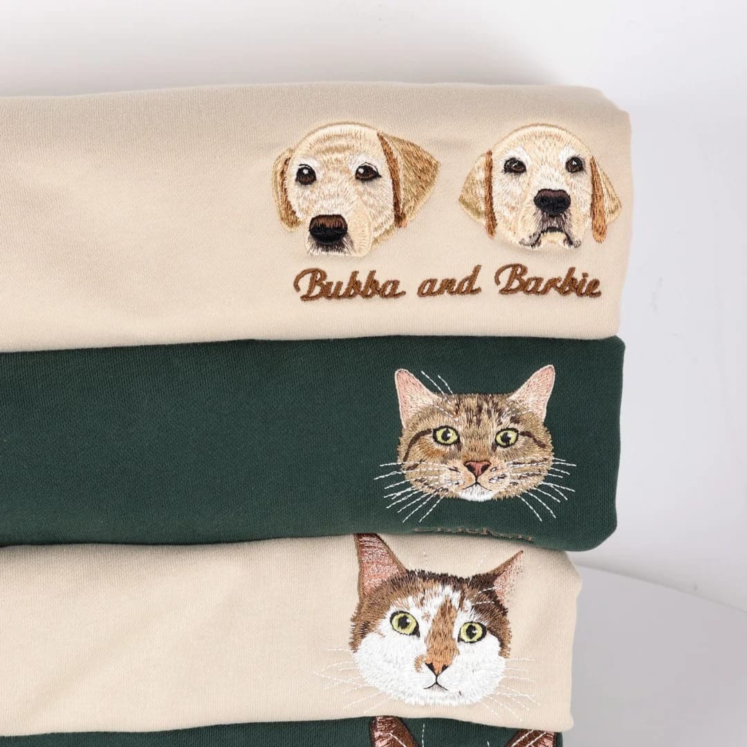 Stack of folded towels with embroidered dog and cat faces on a white background