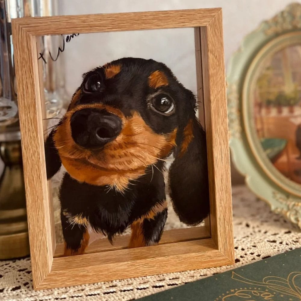 Custom hand-painted dog portrait on glass featuring a black and tan Dachshund puppy in a light wood frame.