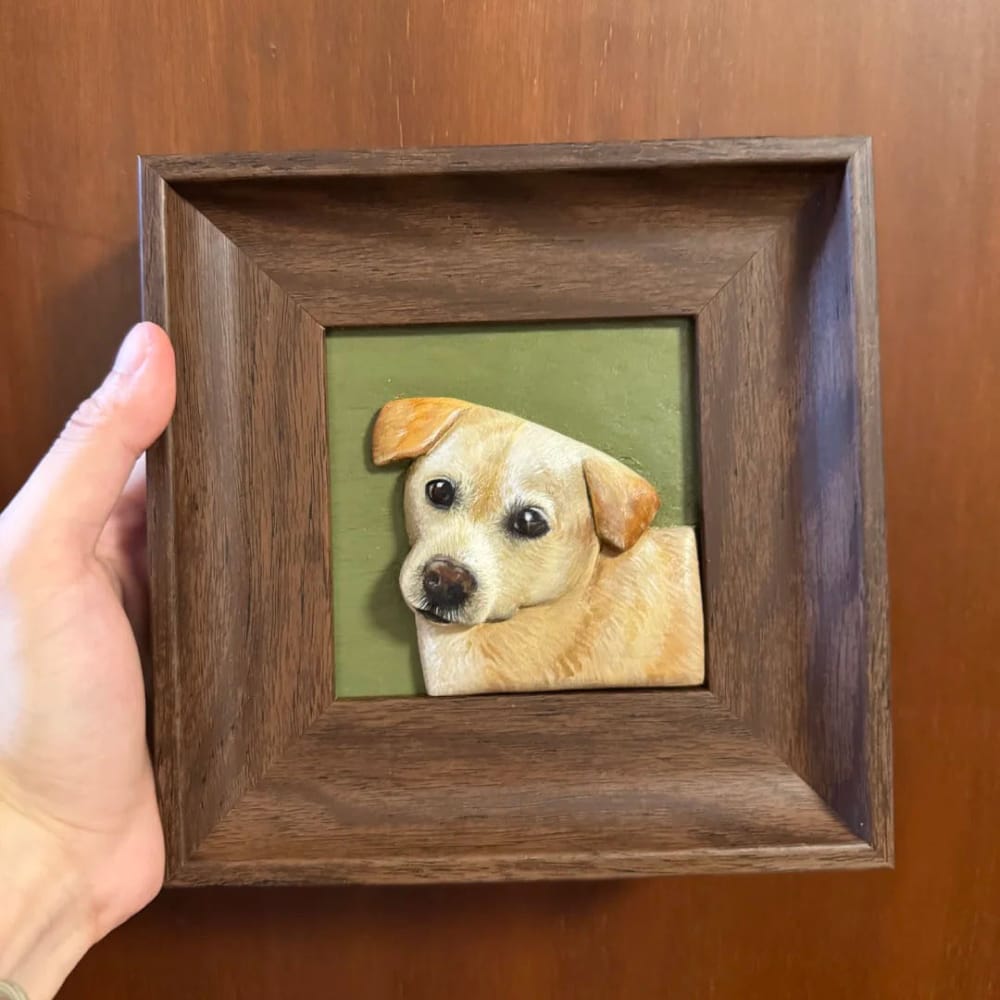 A custom pet portrait wood carving featuring a 3D sculpted tan dog, held in a dark wood frame.