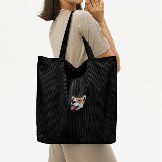 A balck corduroy bag featuring a custom embroidered pet portrait.