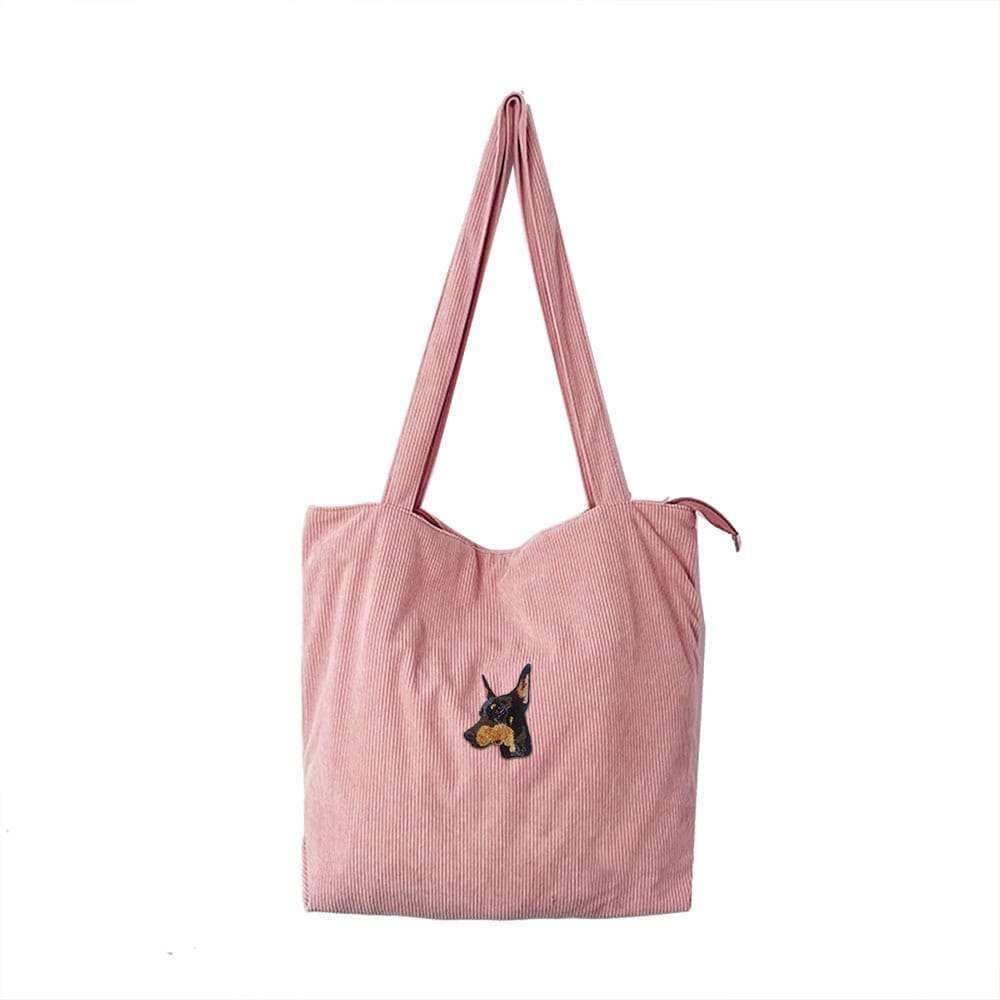 A pink corduroy bag featuring a custom embroidered pet portrait.