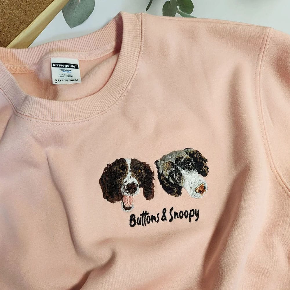 Pink sweatshirt with embroidered dog face and 'Buttons & Snoopy' text on a light background