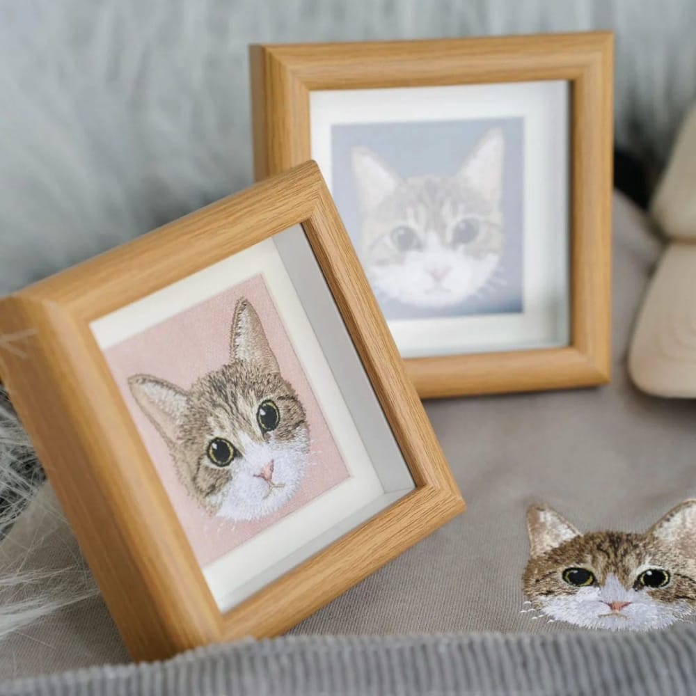 Framed custom embroidered cat portraits in light wood frames displayed as product examples.