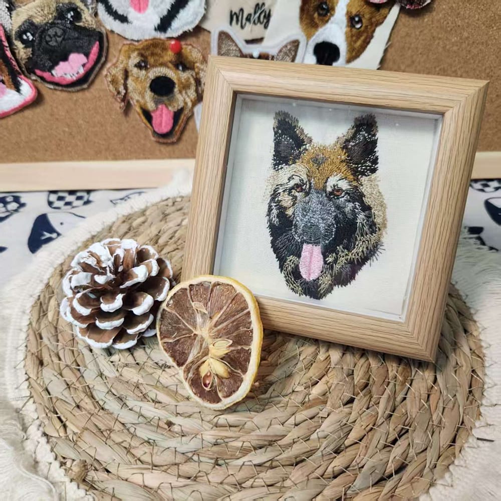 Framed custom embroidered pet portrait of a German Shepherd dog in a light wood frame.