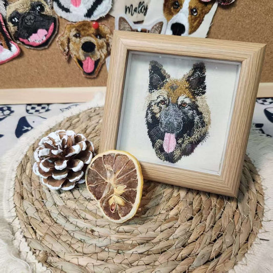 Framed custom embroidered pet portrait of a German Shepherd dog in a light wood frame.