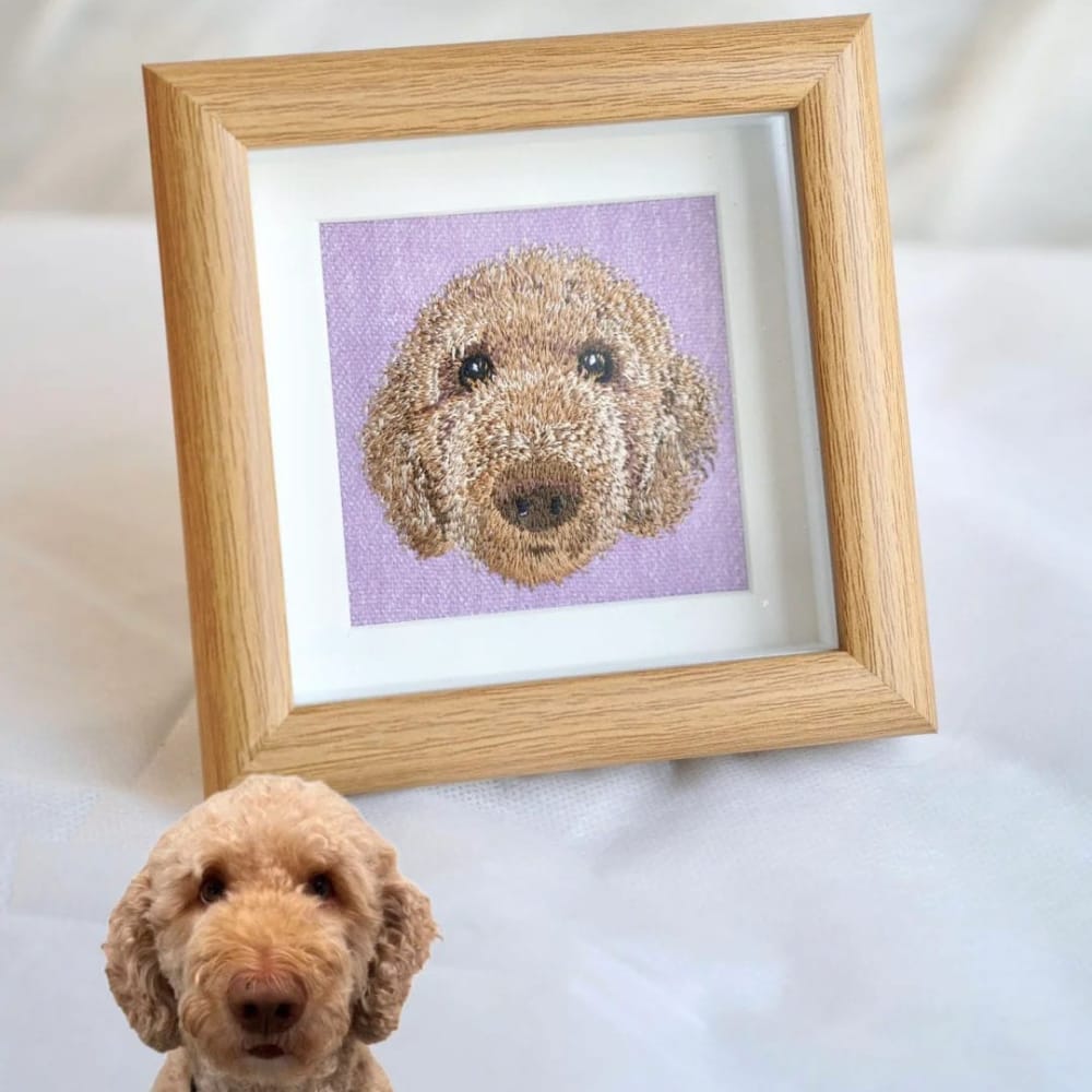 Framed custom embroidered dog portrait of a brown Poodle on a purple background in a light wood frame.