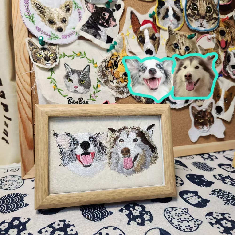 A framed custom embroidered pet portrait featuring two smiling dogs, a Border Collie and a Husky, in a light wood frame.