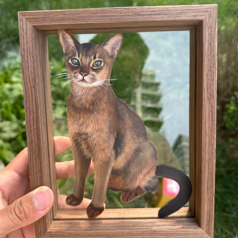 Personalized pet portrait on single-layer glass featuring a custom hand-painting of a brown cat, held in a wood frame.